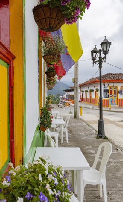 Calle colorida de un pueblo colonial en Colombia con fachadas tradicionales, flores y ambiente turístic