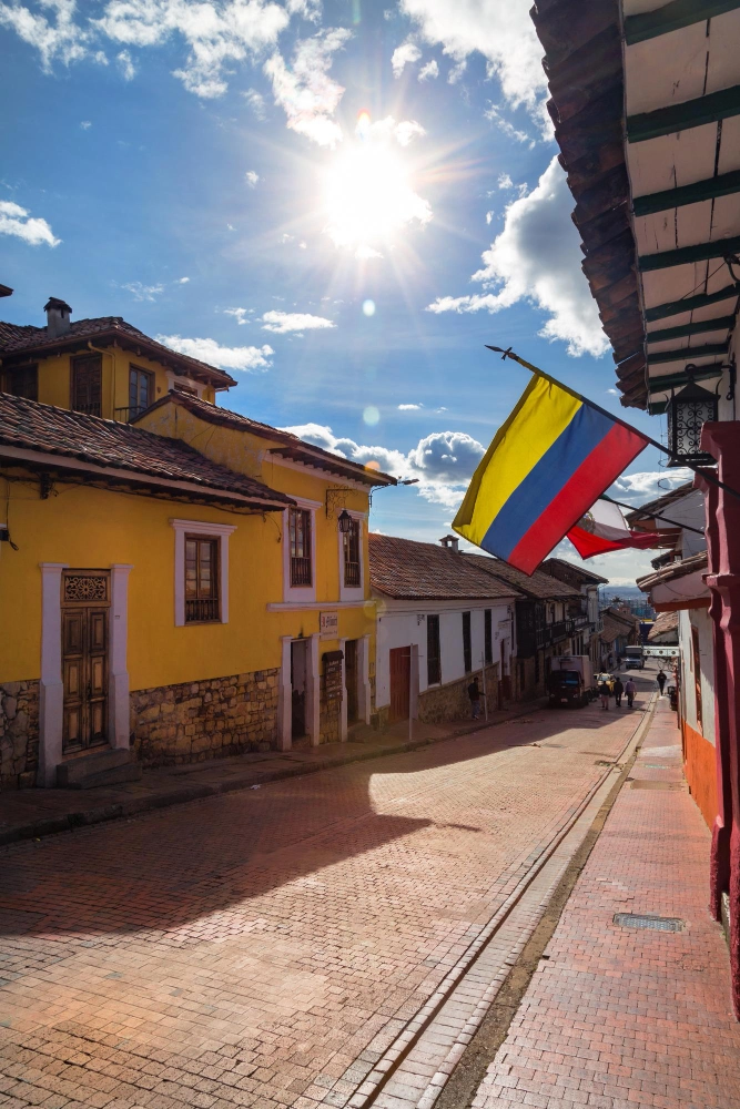 Calle colonial en Colombia con bandera colombiana, casas antiguas y cielo despejado en un destino turístico