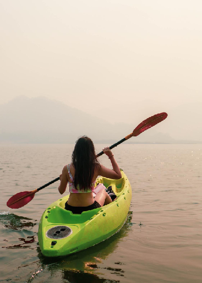 Mujer remando en kayak sobre aguas tranquilas en Colombia durante una actividad de ecoturismo y aventura al aire libre