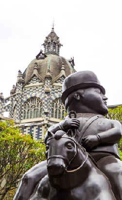 Escultura de Plaza Botero en Medellín con arquitectura histórica al fondo, lugar turístico y cultural de Antioquia